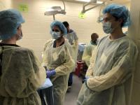 Three trainees in scrubs standing at a station at the New York City Regional Urogynecology Fellows Course.